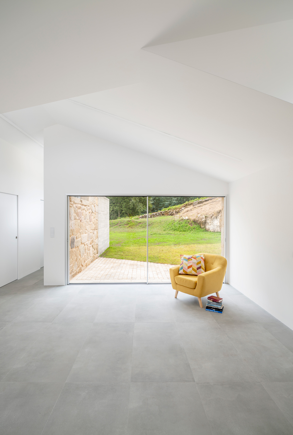 Interior de diseño minimalista con gran ventanal al jardín en Vivienda Unifamiliar Casal do Mendo. Espacio exclusivo diseñado por Crudo Arquitectura en Pontevedra.