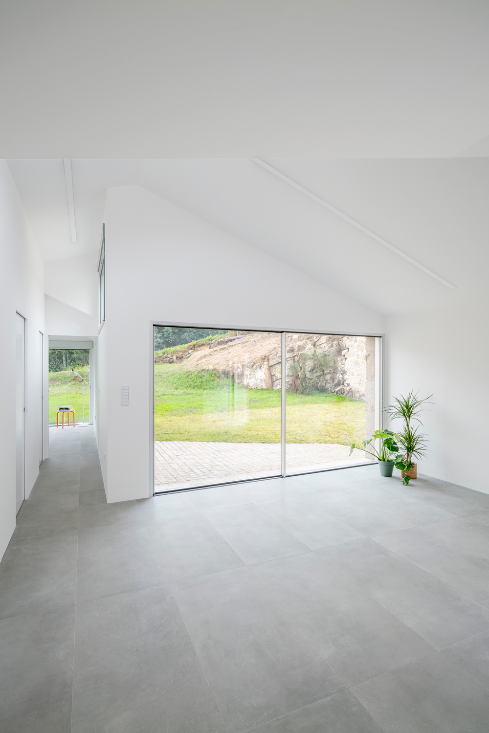 Interior de diseño minimalista con gran ventanal al jardín en Vivienda Unifamiliar Casal do Mendo. Espacio exclusivo diseñado por Crudo Arquitectura en Pontevedra.