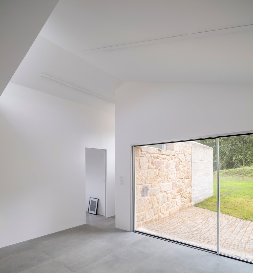Interior de diseño minimalista con gran ventanal al paisaje en Vivienda Unifamiliar Casal do Mendo. Un espacio exclusivo creado por Crudo Arquitectura en Pontevedra.